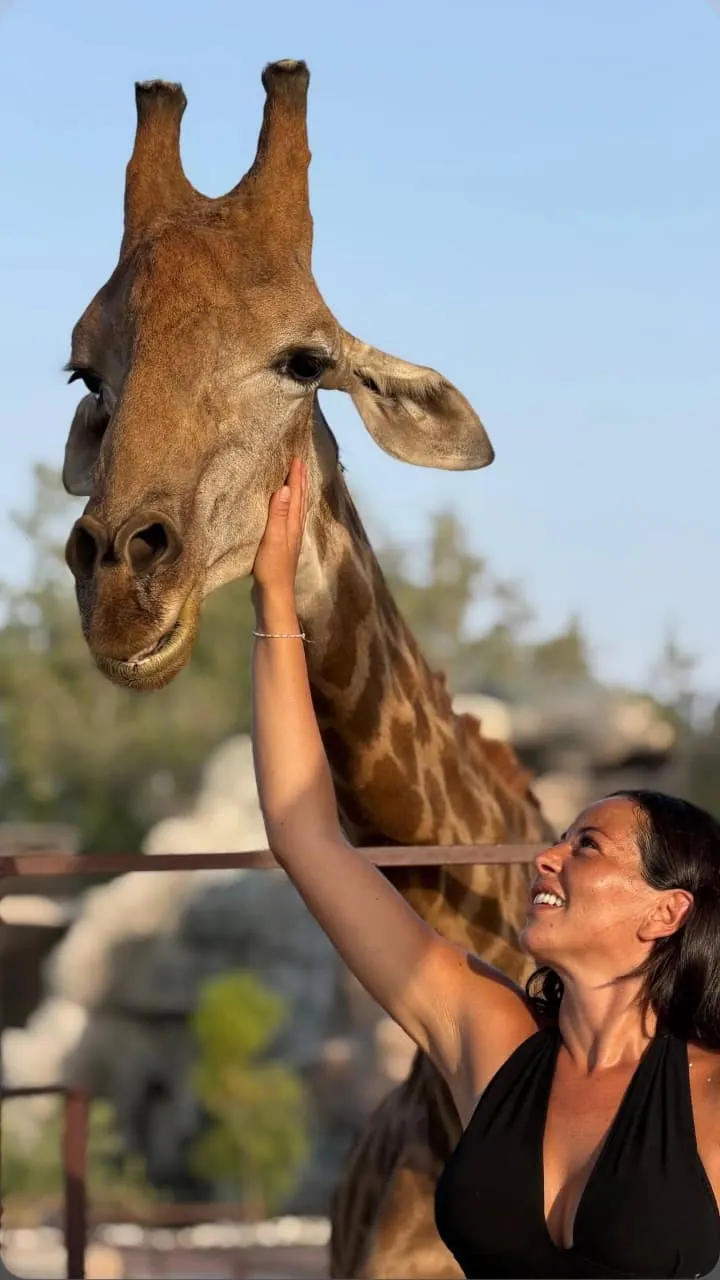 Une visiteuse caresse une girafe à Noor Jungle